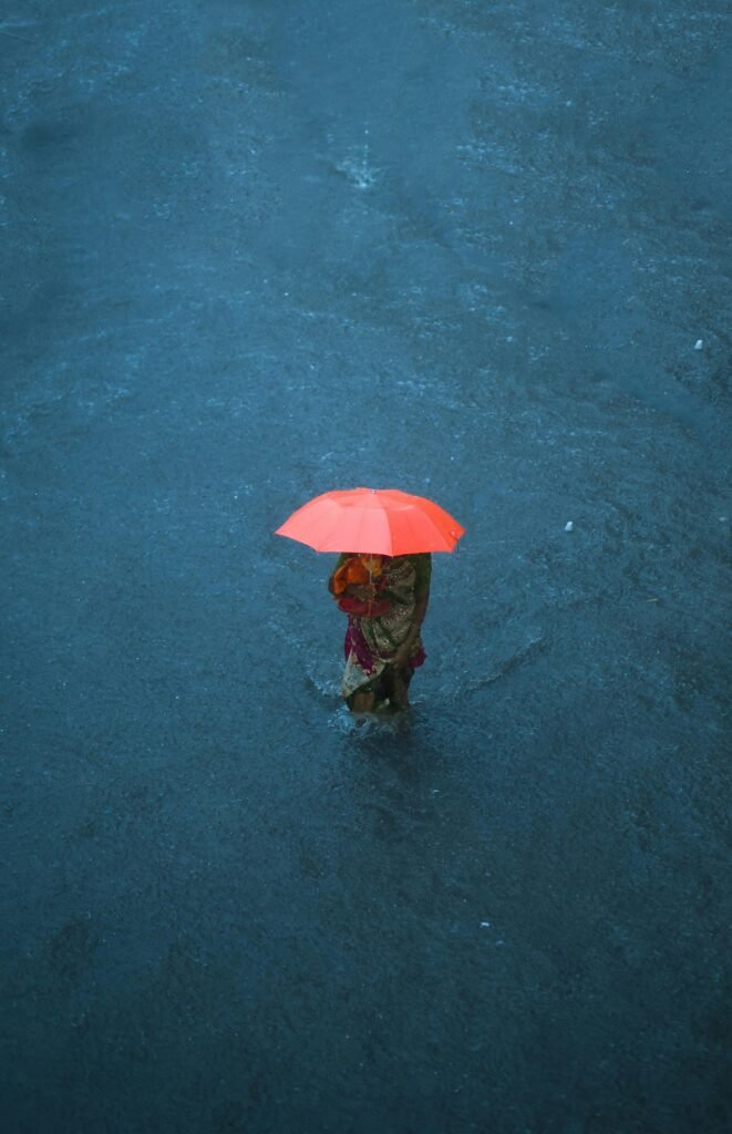 A woman with an orange umbrella stands amid a monsoon flood in Navsari, India.